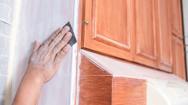 Person sanding kitchen cabinets