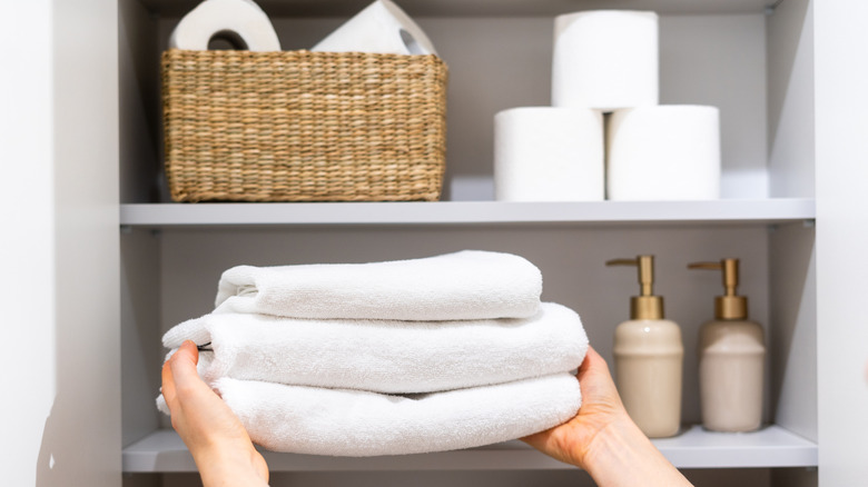 Feminine hands placing folded towels inside a linen closet