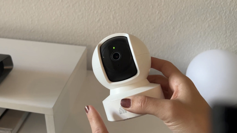 Woman holding white security camera