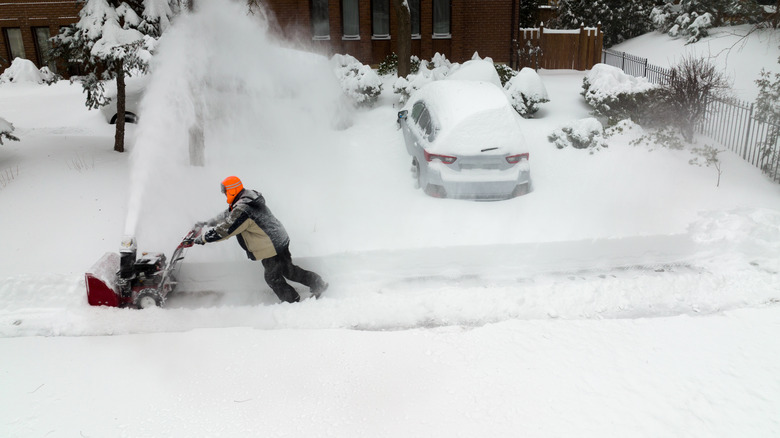 Person using a snow blower on a sidewalk