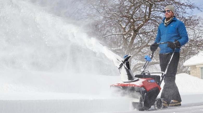 Man blowing snow along a sidewalk with a Toro snow blower