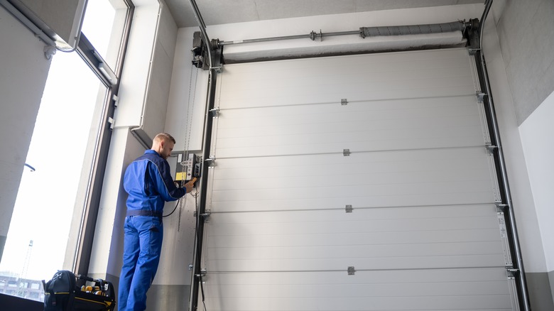 Man in blue overalls working on controls of jackshaft garage door opener