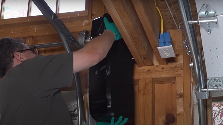 Man wearing gloves installing a jackshaft garage door opener system