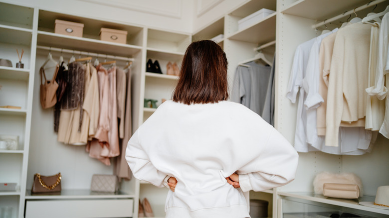 A person standing and contemplating inside a walk in closet