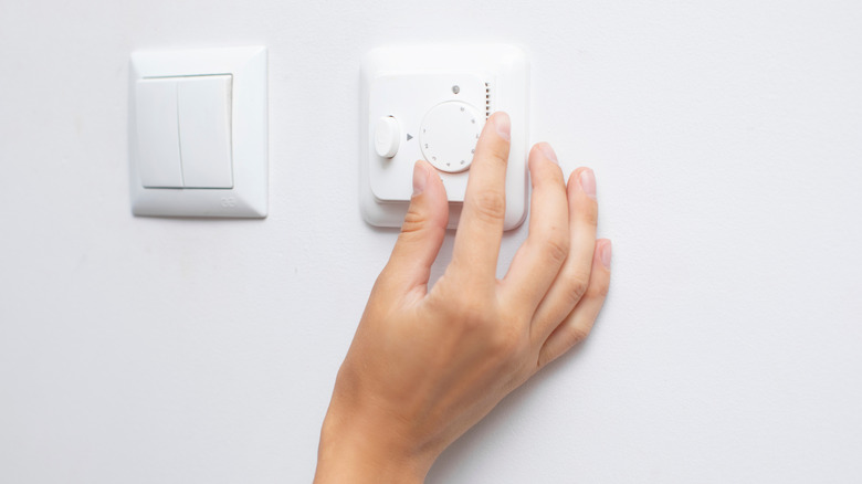 A person adjusting a dimmer switch for the lights