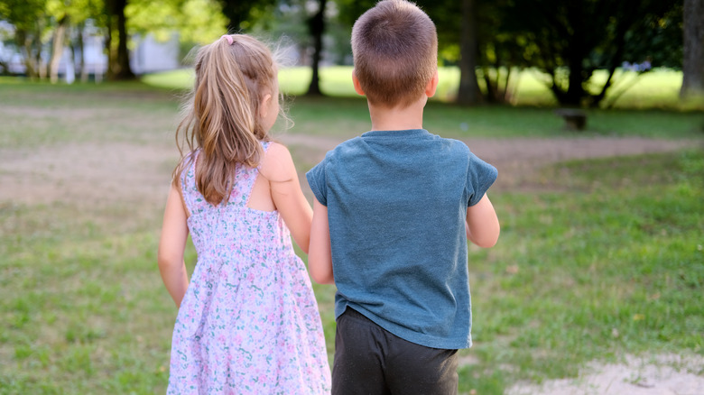 Two children walk in a park