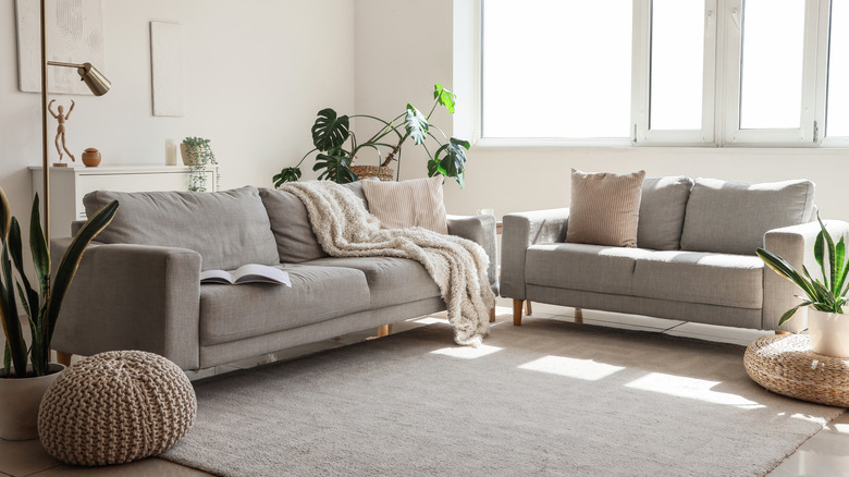 A gray rug on a wooden living room floor under a sectional sofa and table