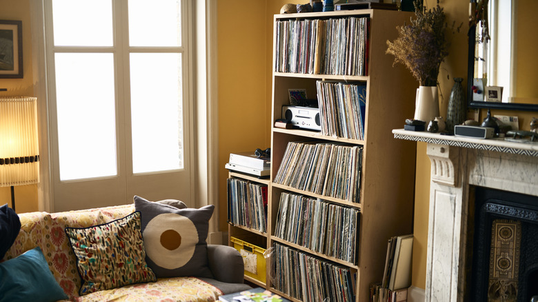 Living room with shelf full of records against wall next to marble fireplace