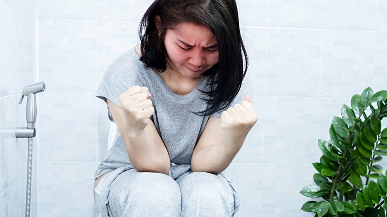 Woman uncomfortable on toilet