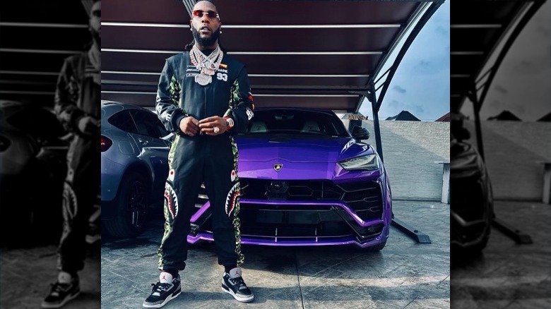 Burna Boy poses next to his cars 