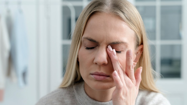 Woman rubs irritated eyes