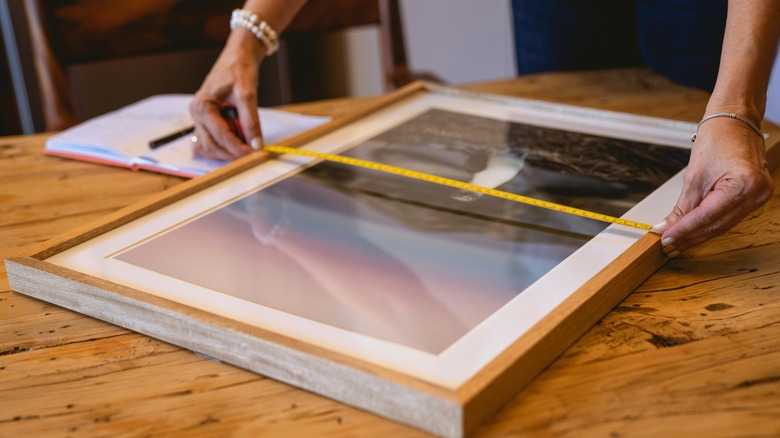 woman measuring a picture frame