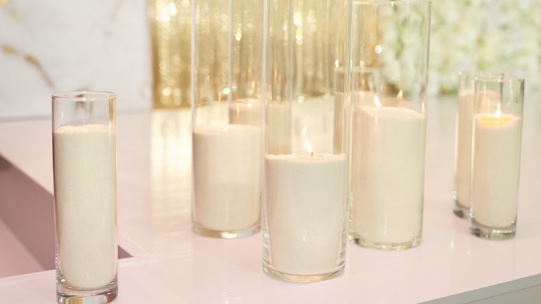 Varying sizes of tall white candles in jars