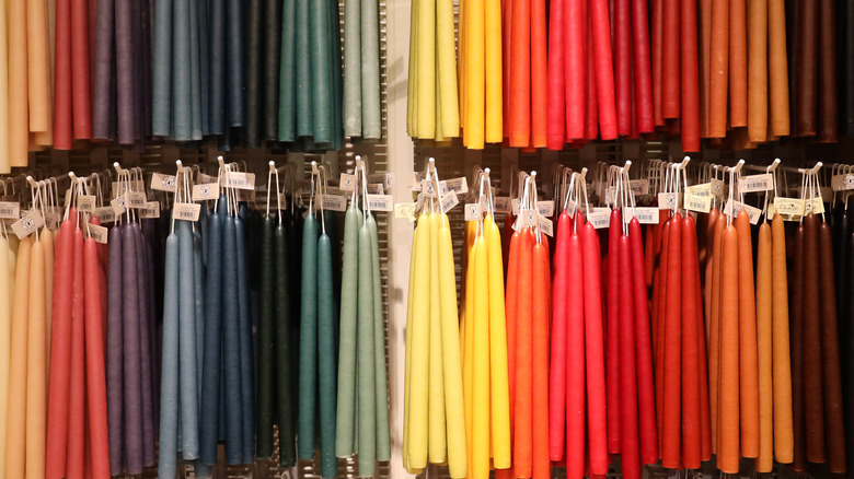 Rows of colorful taper candles are displayed