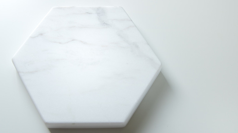 A hexagonal marble coaster is shown in a product photo