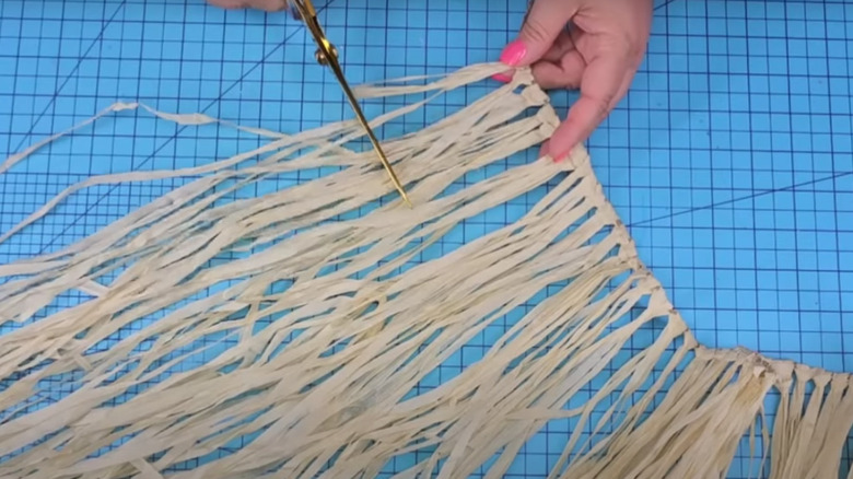 Hand cutting grass skirt