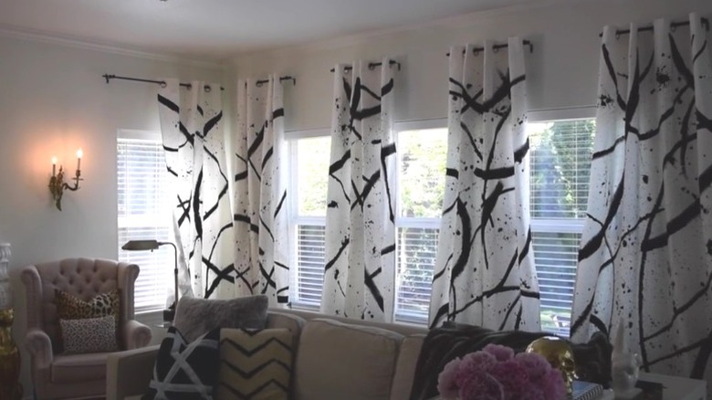 White curtains with painted black design hanging in living room