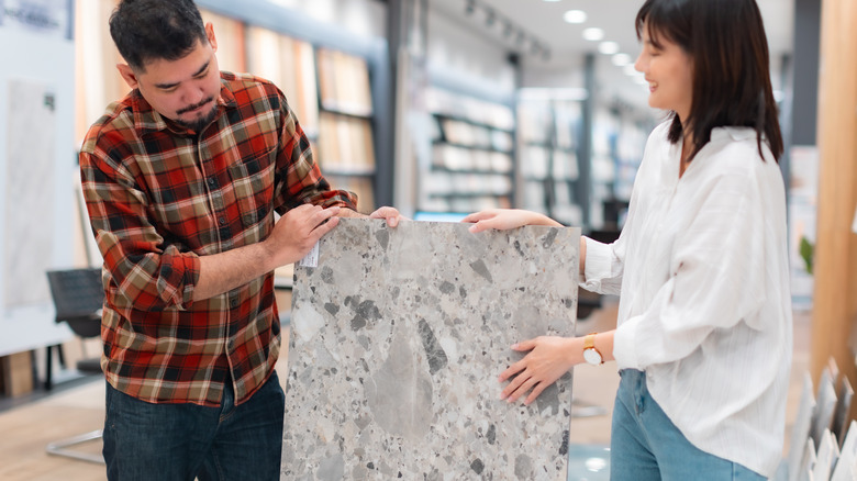 Two people holding and admiring a large stone tile.