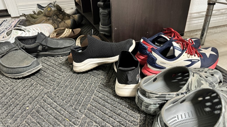 Many shoes of different types rest on a rug near cubby storage