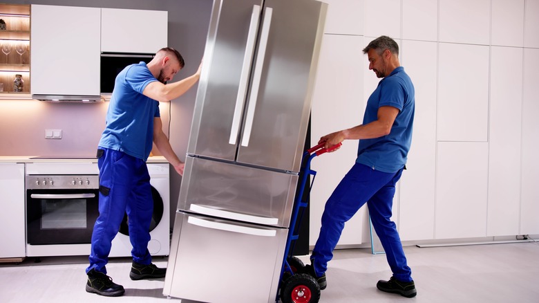 Men moving fridge with dolly