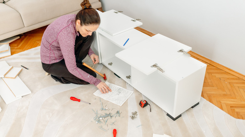 A woman building a white cabinet in her living room