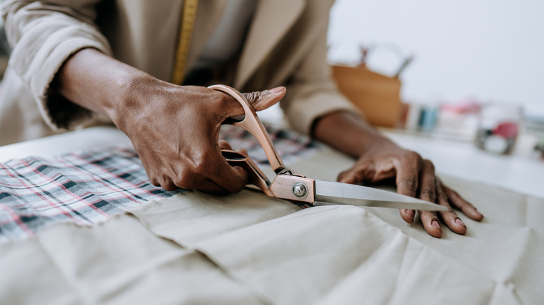 person cutting fabric with scissors