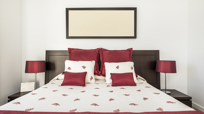 A bed with deep red and white bedding sits in a bedroom