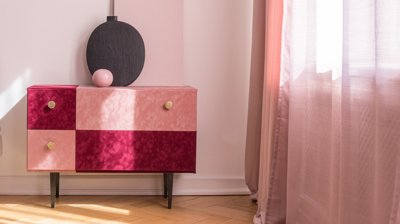 A velvet pink and deep red end table stands in a room