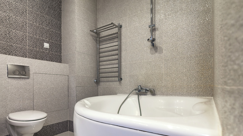 A corner bath and shower combination fixture in a bathroom.