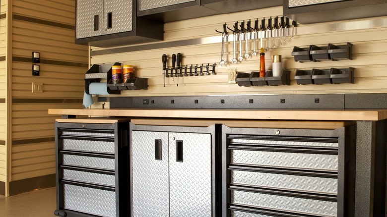 metal garage workbench with wood countertop under metal wall cabinets