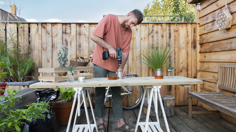 man drilling holes in pot