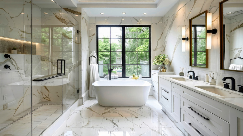 Bathroom with bathtub, sinks, cabinets, and lighting fixtures