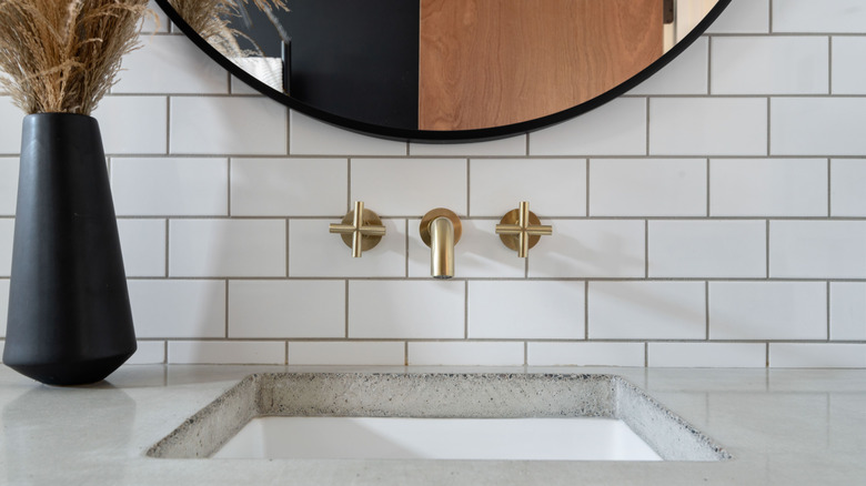 Bathroom with undermount sink, mirror on the wall and a vase