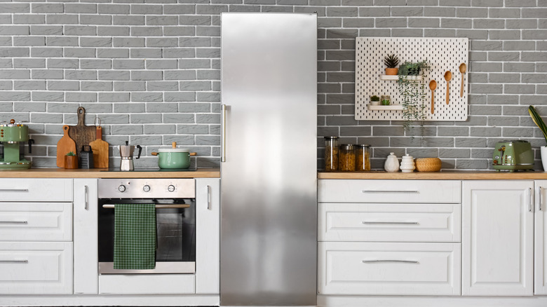 Modern kitchen with stove and refrigerator against gray brick wall