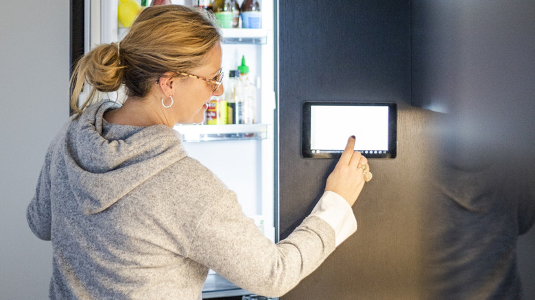 Woman using the touchscreen in a smart refrigerator