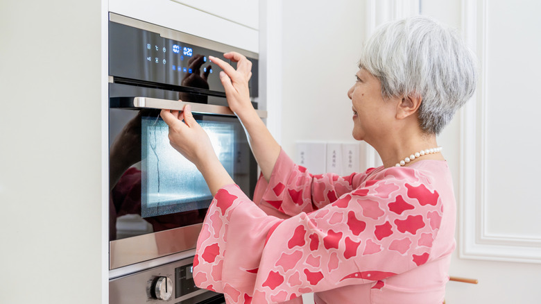 Older woman adjusts smart oven on touchscreen