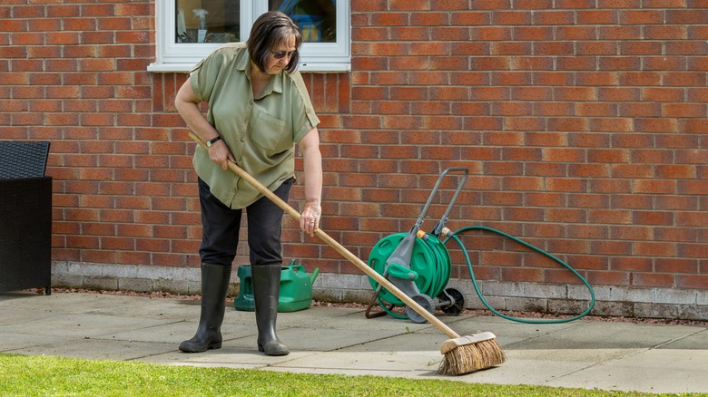 woman sweeping her patio pavers