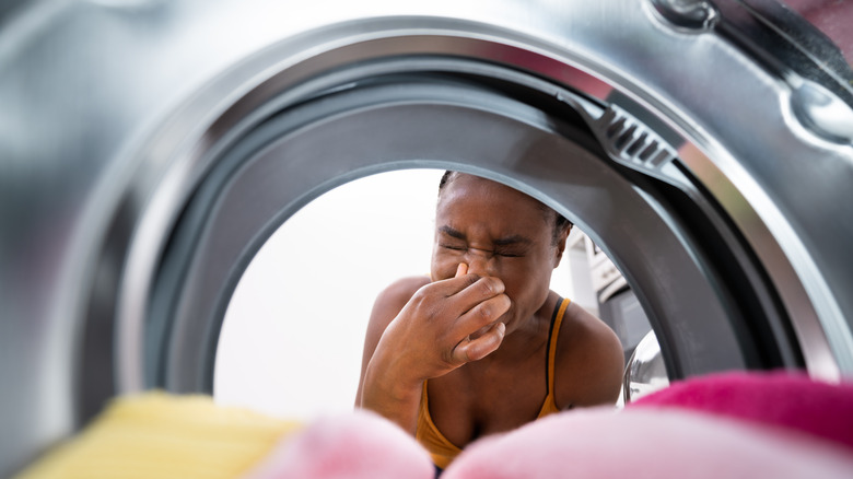 Woman holding nose by washer