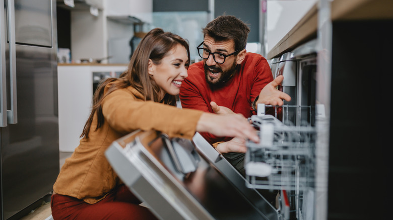 Woman and man looking inside dishwasher in store