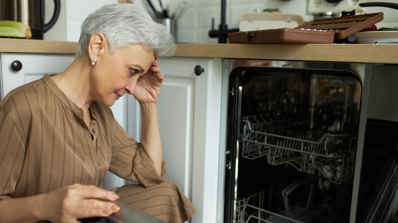 Frustrated woman looking into dishwasher