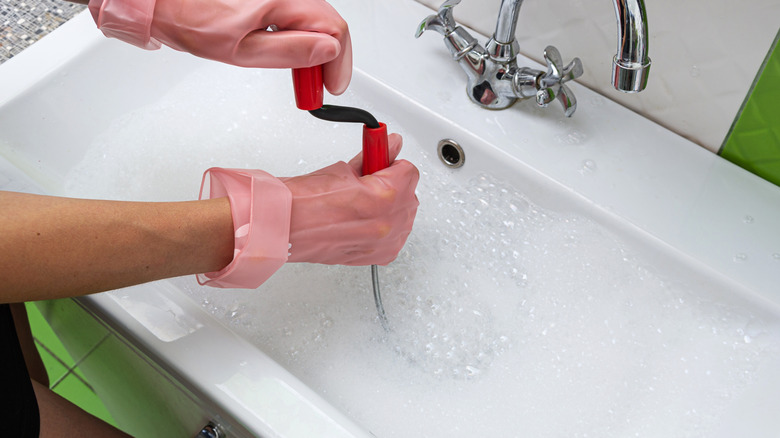 A person snaking a drain