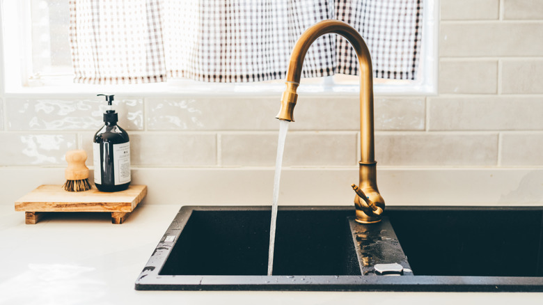 A gold faucet with water coming out