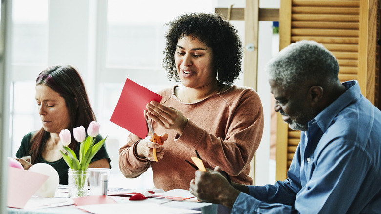 Three people working at a table on paper crafts