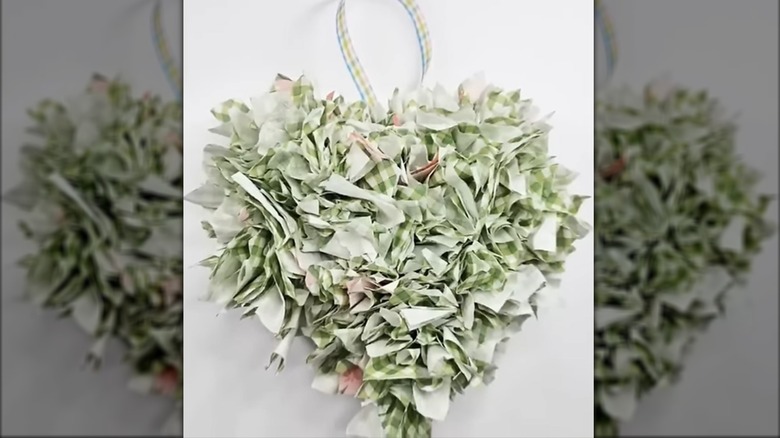 crafter trimming up the final product of a foam heart covered with napkin florets