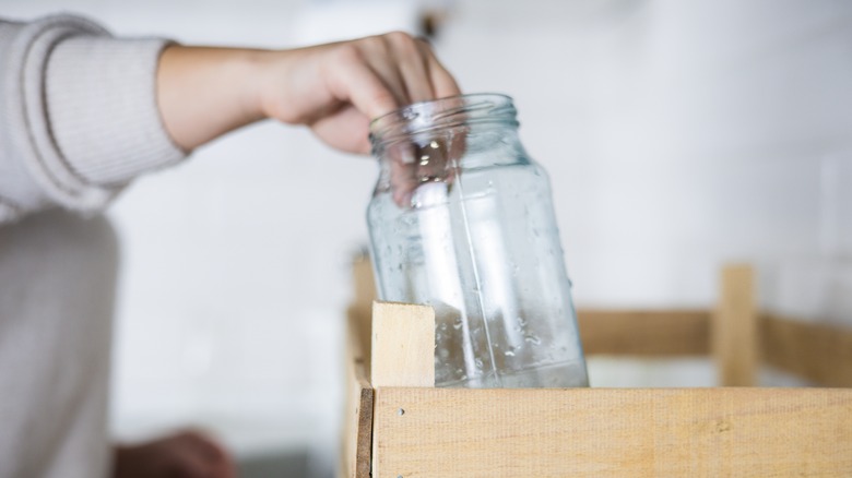 Person grabbing glass jar