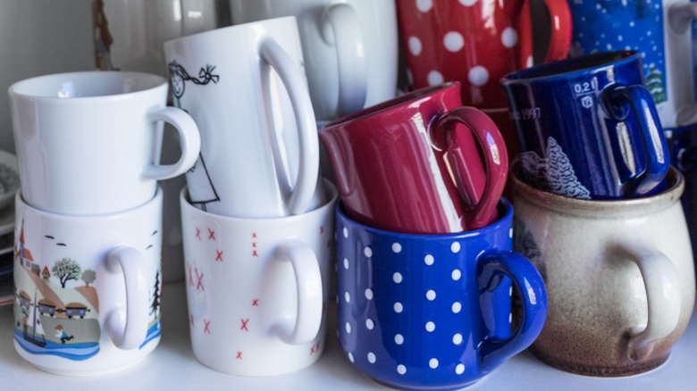 Disorganized coffee mugs sitting in a kitchen cabinet