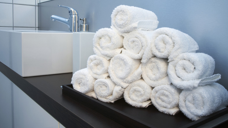 White hand towels rolled and stacked on bathroom counter