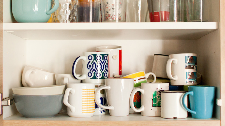 An open cabinet, packed with mugs and glasses.