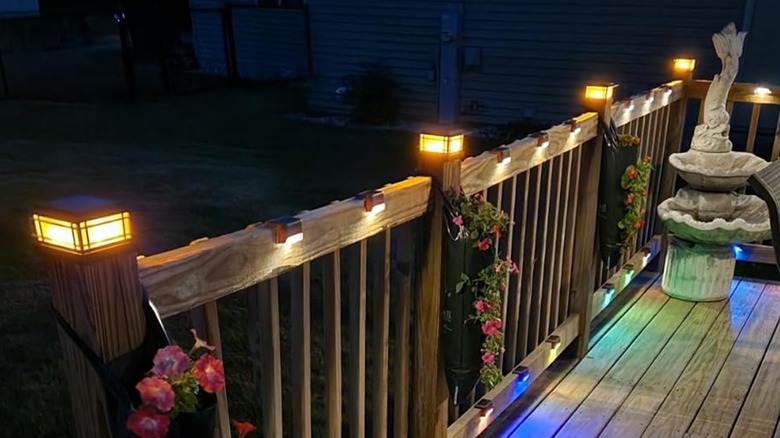 Flickering light fence post caps are installed on a porch railing