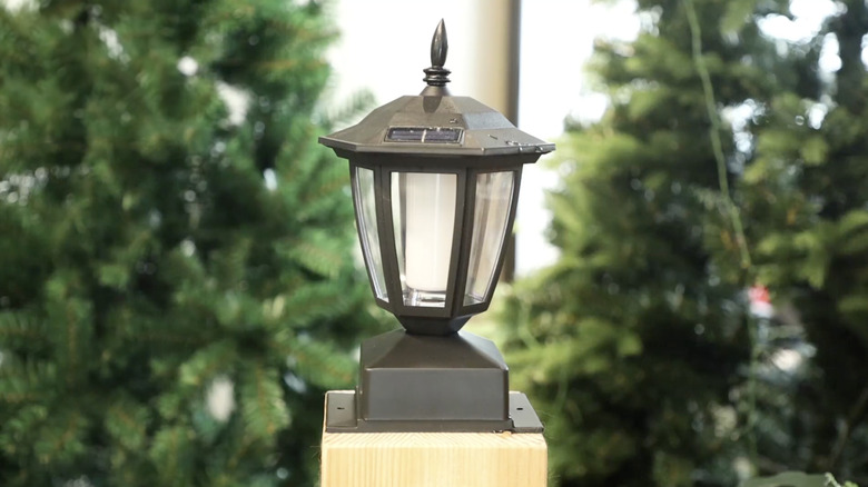 Two flickering-effect solar-powered fence post caps are shown in the rain